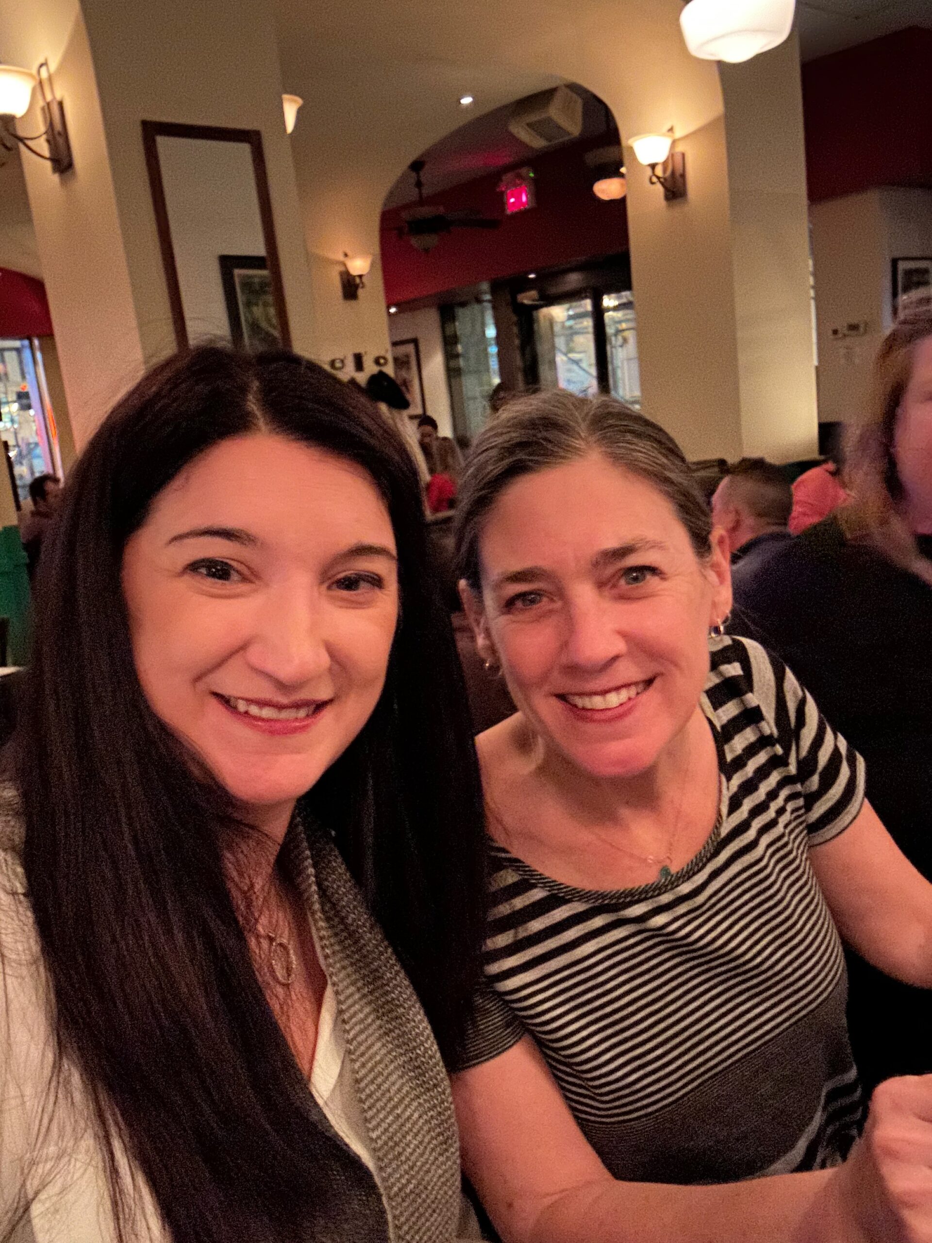 two women smiling while having dinner.