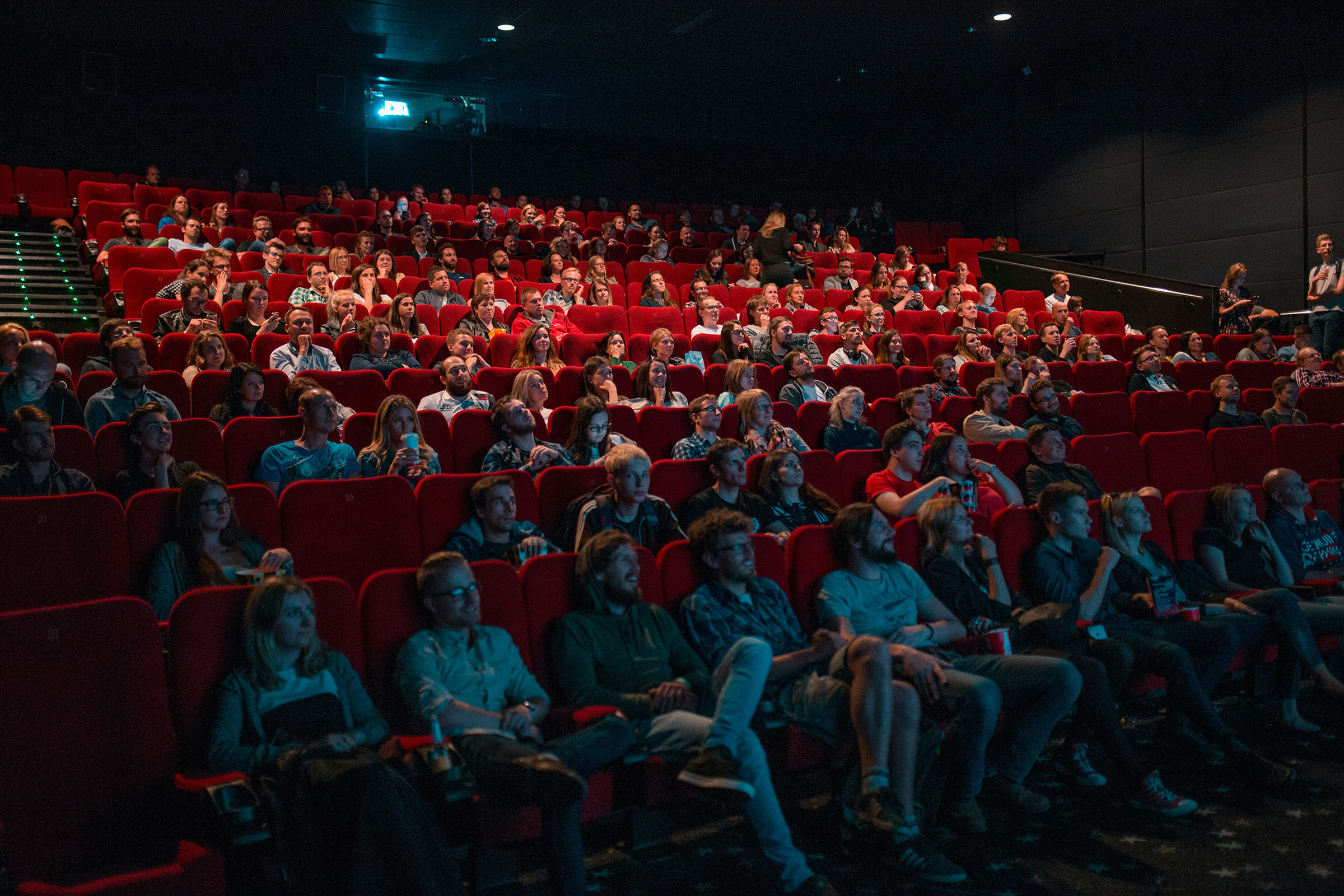 krists-luhaers-AtPWnYNDJnM-unsplash Audience in movie theatre looking at a screen.